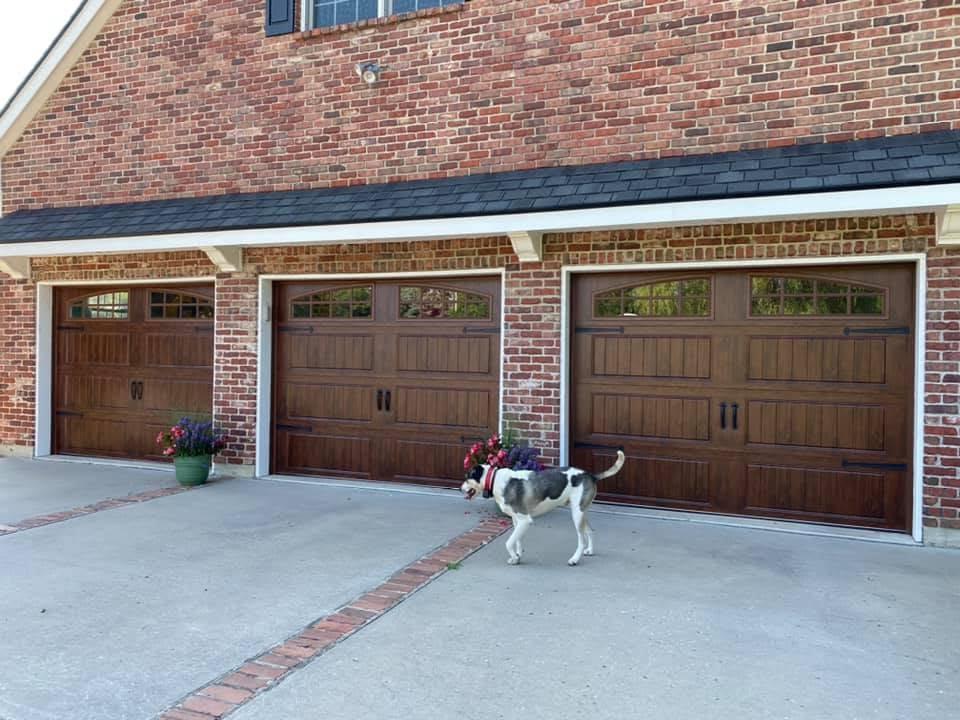Carriage-style wood-grain garage doors on a brick home
